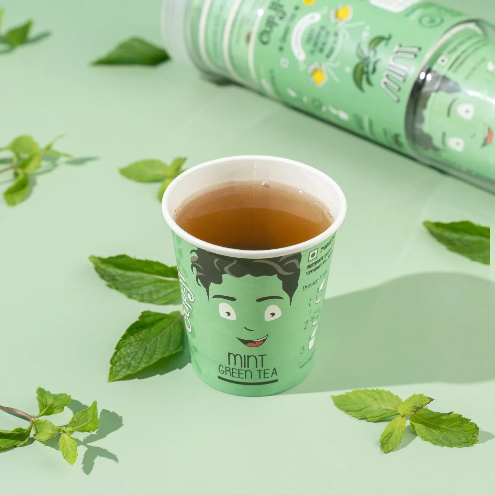 Overhead flatlay of a brewed Fennel cup on a green mat with fennel seeds, star anise and the jar.