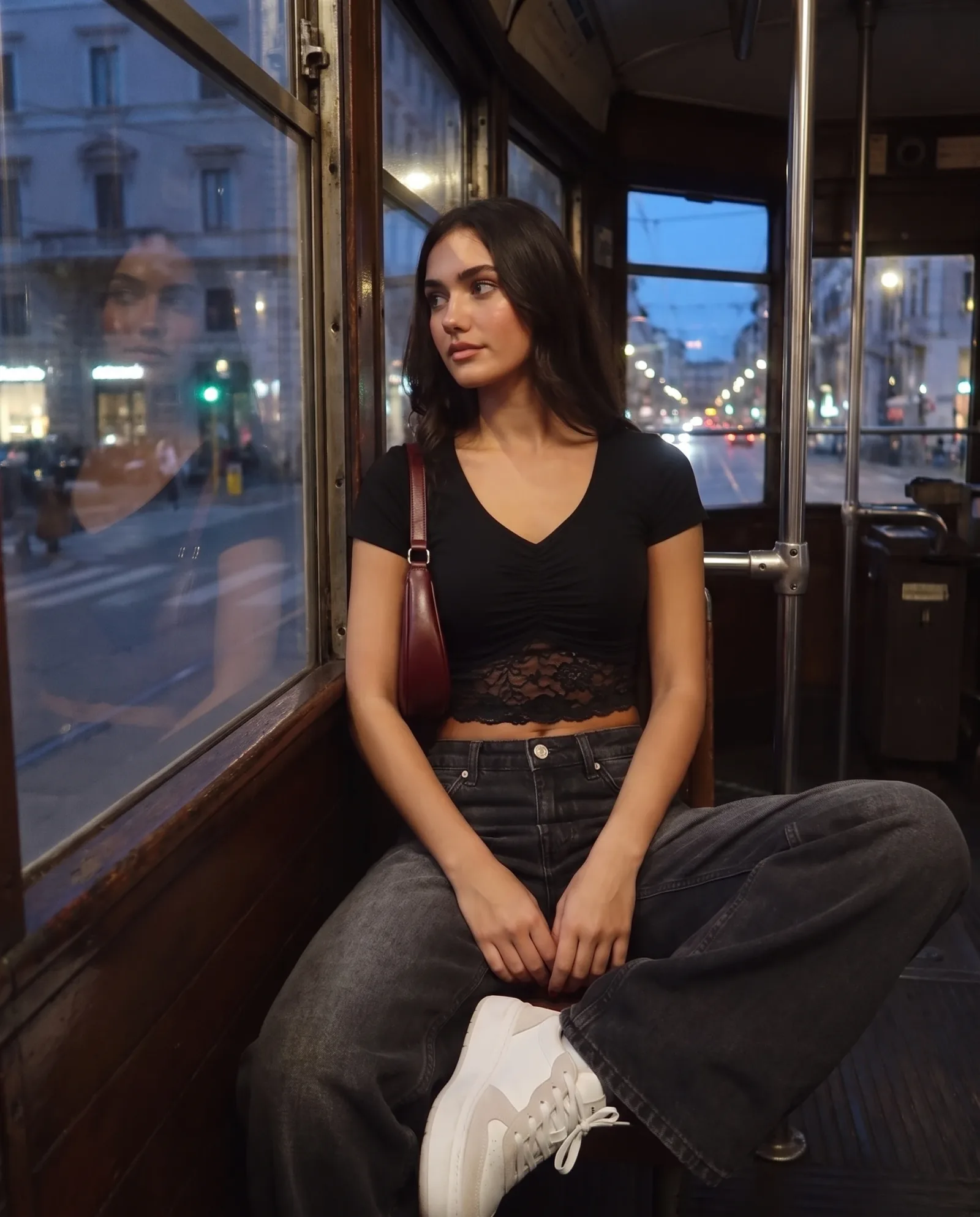 Black v-neck lace-trim crop top, seated inside a vintage tram looking out at the street.