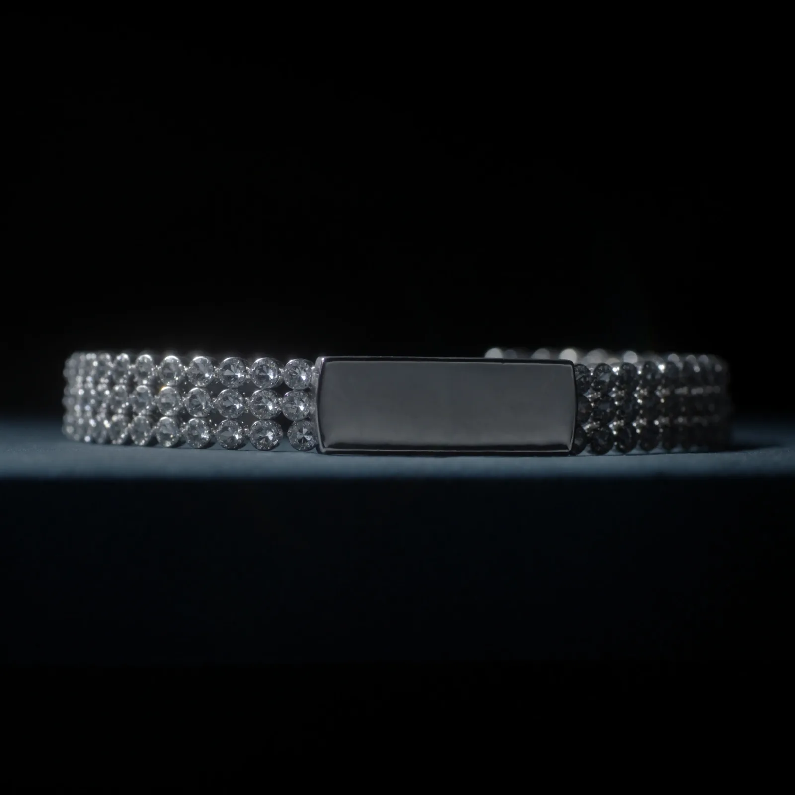 Diamond ID bracelet with a plain polished engravable bar between three rows of prong-set stones, on black.