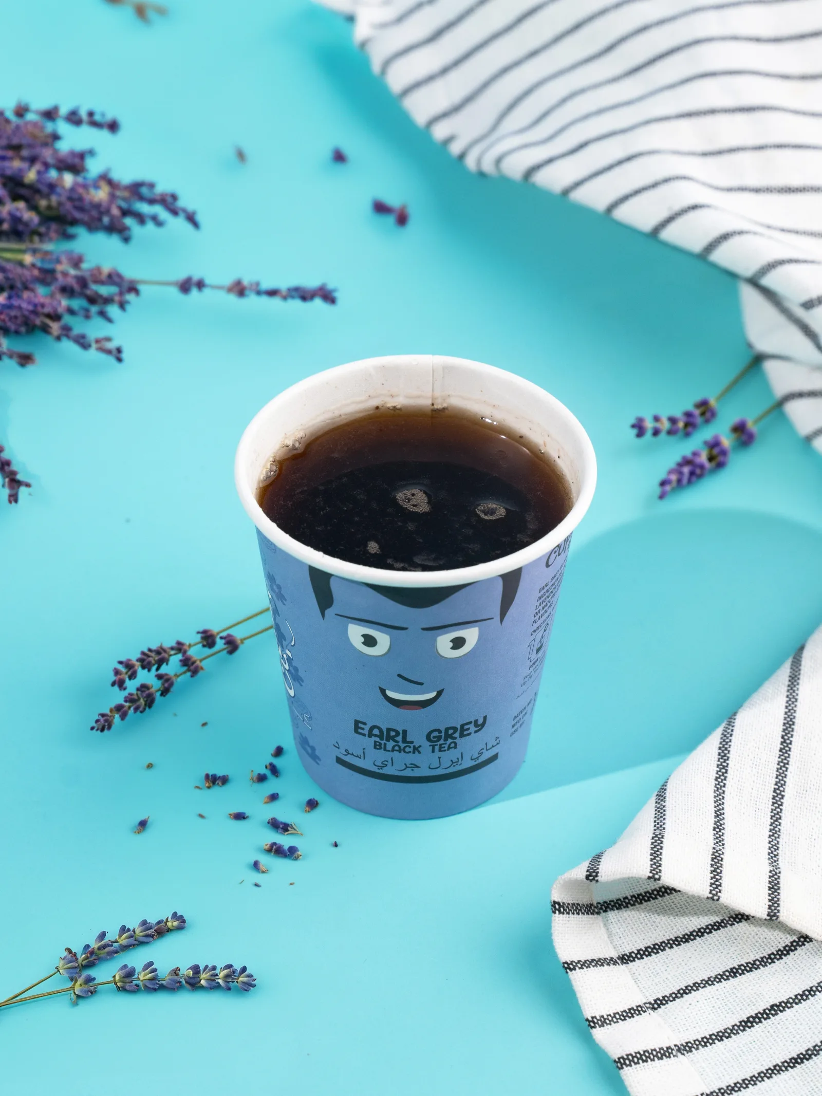 Brewed Earl Grey cup on a teal surface with lavender sprigs and a striped cloth.