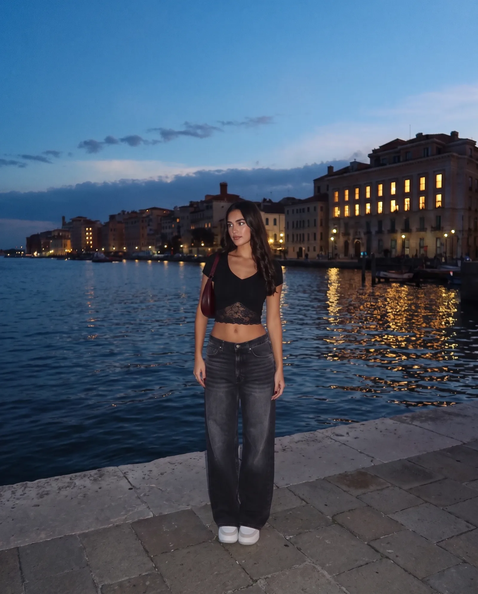 Black v-neck lace-trim crop top with jeans, full length, against a waterfront town.