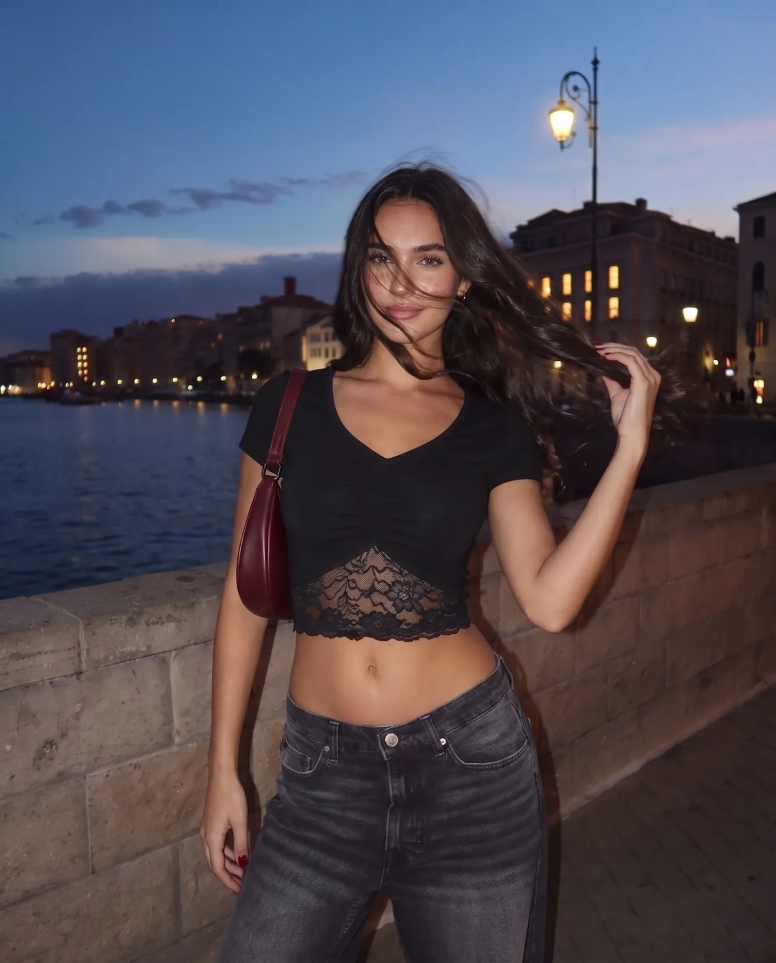 Close portrait in the black v-neck crop top, wind-blown hair, hand lifted to the hair.