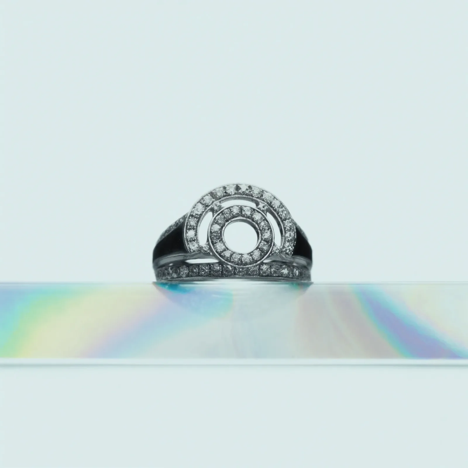 Circular openwork pavé diamond ring with concentric rings of stones, on a pale blue background.