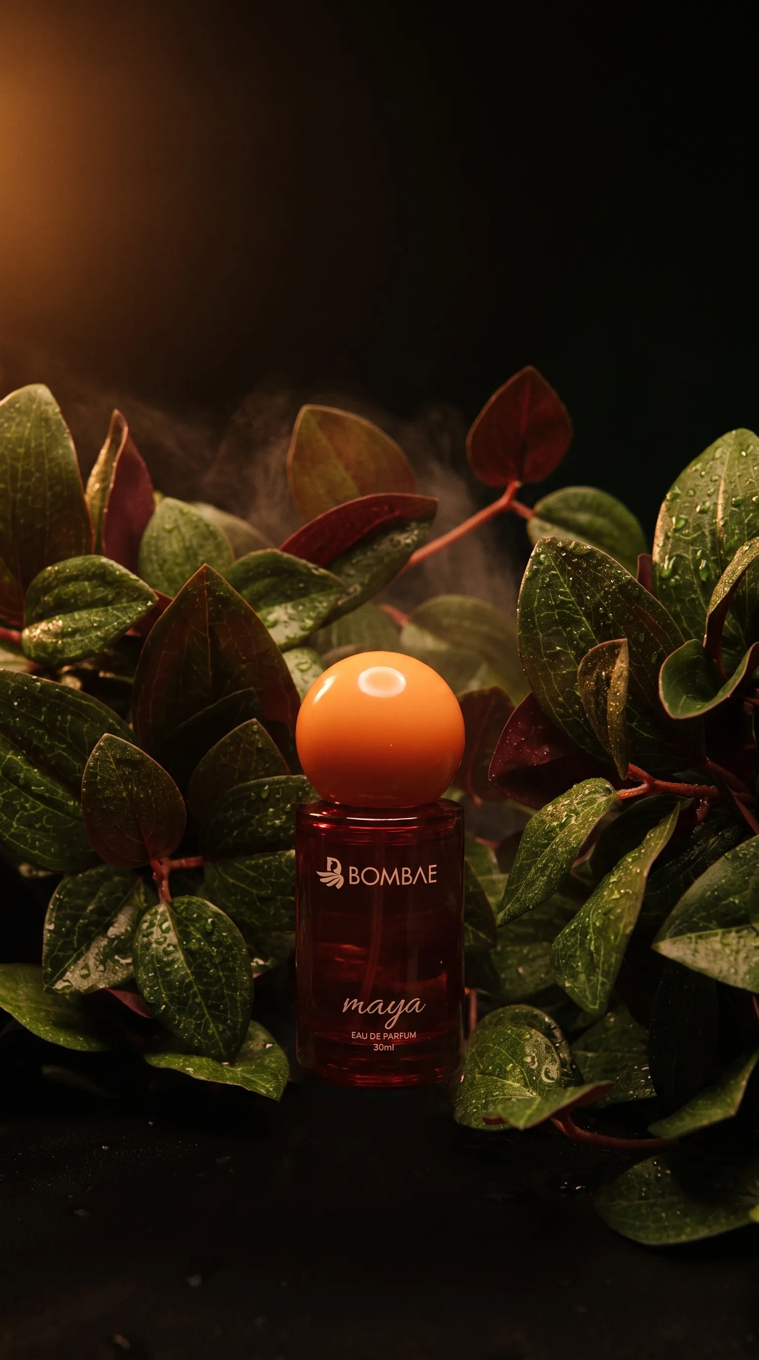 Bombae Maya perfume bottle surrounded symmetrically by wet foliage and rising mist, label reading Bombae Maya Eau de Parfum 30ml.