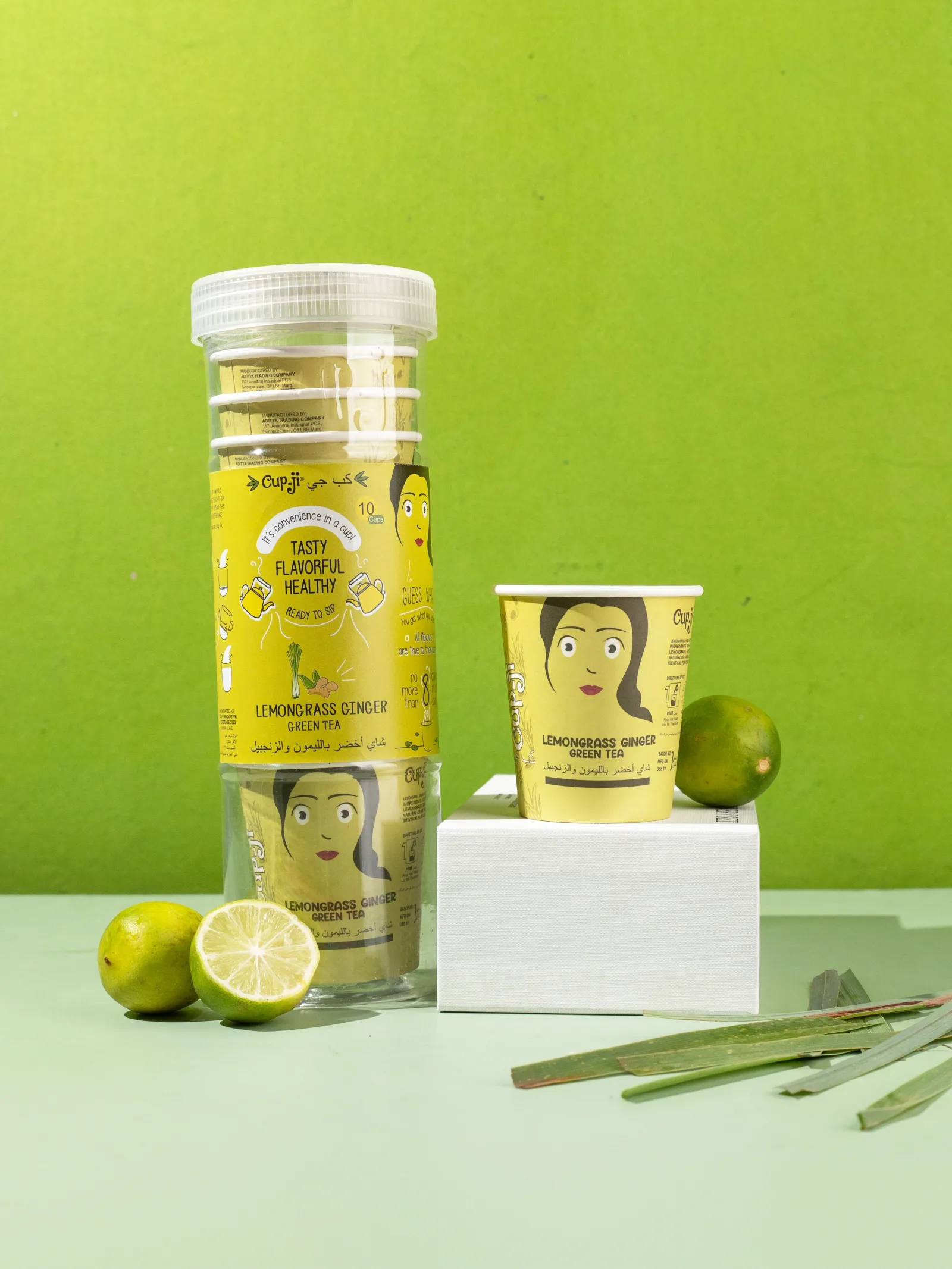 Lemongrass Ginger jar and cup on a lime green ground with lemongrass stalks and limes.