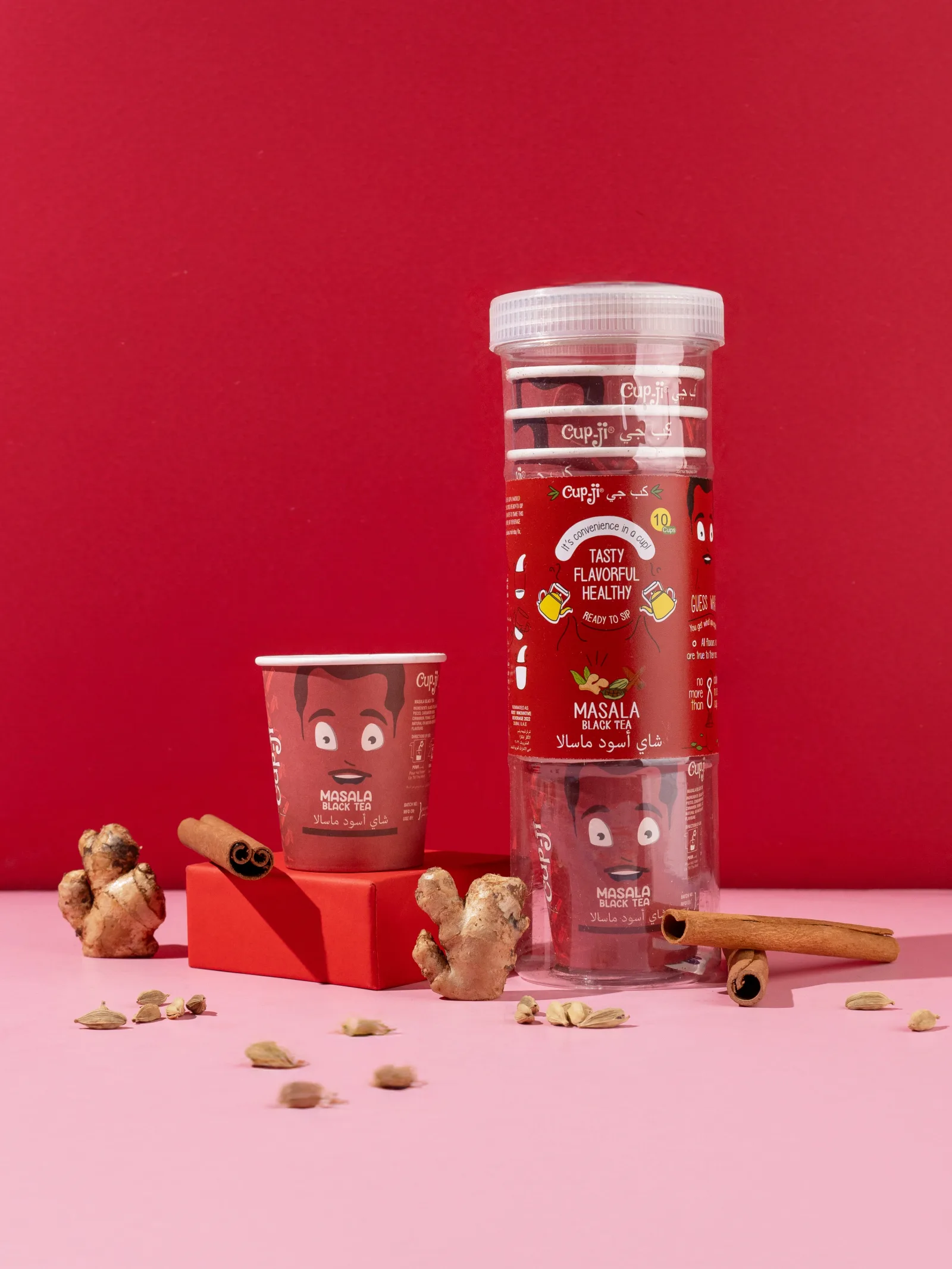 Masala Black Tea jar and cup on a deep red ground with cinnamon bark and ginger.